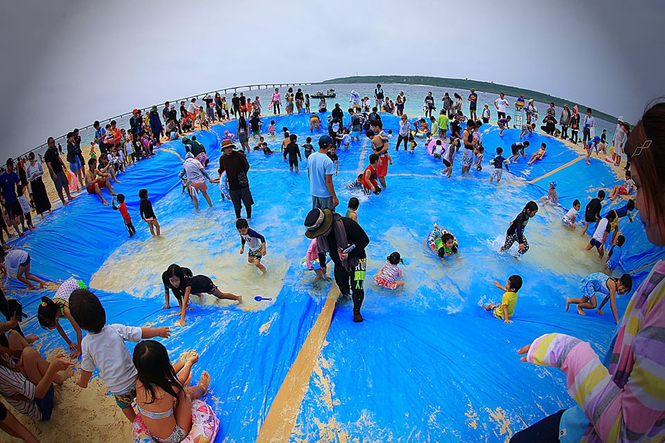 宮古島の海辺で子どもたちと地域の人々が集まる行事の風景